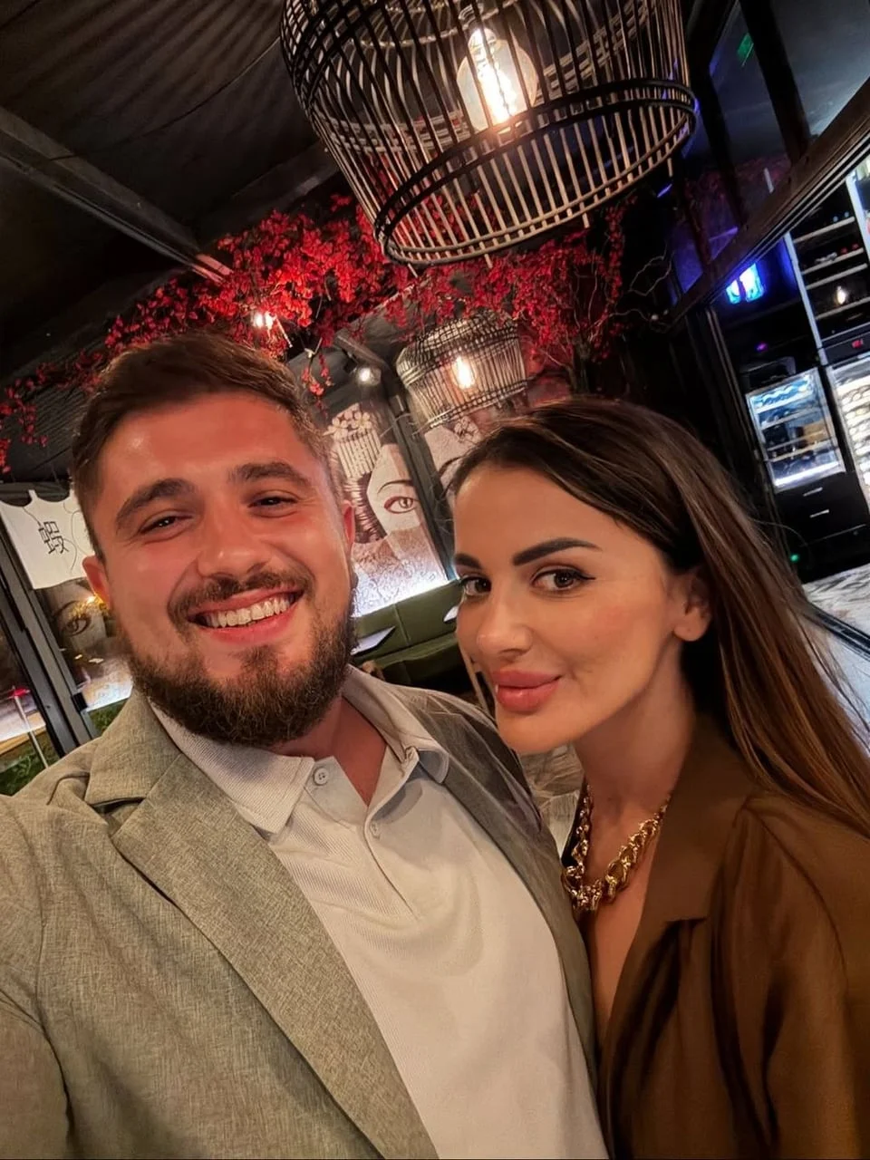 Selfie nasmijanog muškarca i žene u restoranu s crvenim cvećem