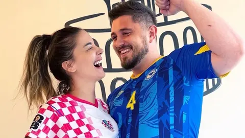 Osmijana žena u crveno-bijelom dresu i muškarac u plavom dresu