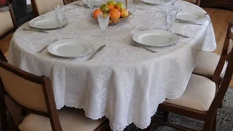 Okrugli stol s bijelim čipkastim stolnjakom i voćnim pladnjevima