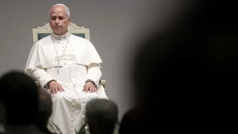 Papa Franjo u bijelom odjeću sjedi na ukrašenom stolcu