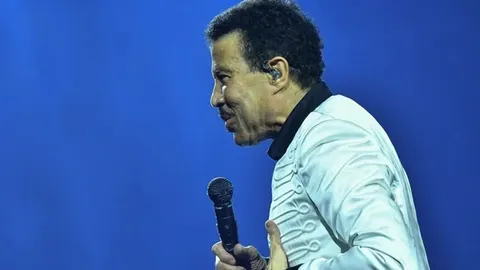 Lionel Richie u bijeloj jakni drži mikrofon na sceni