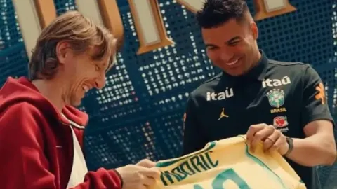 Nasmijani Luka Modrić i Casemiro drže žuti dres s natpisom Modrić.