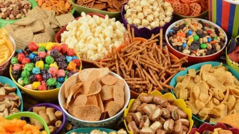 Razne vrste nezdravih grickalica, čipsa i štapića u šarenim zdjelicama.