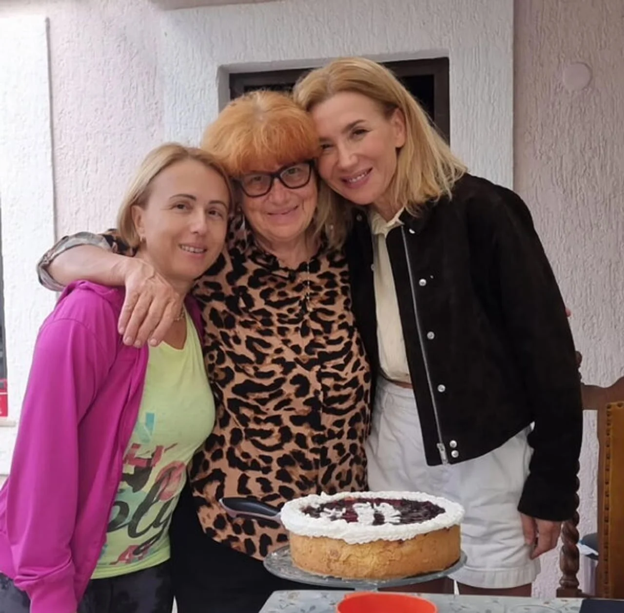 Tri žene u zagrljaju uz domaći kolač na stolu