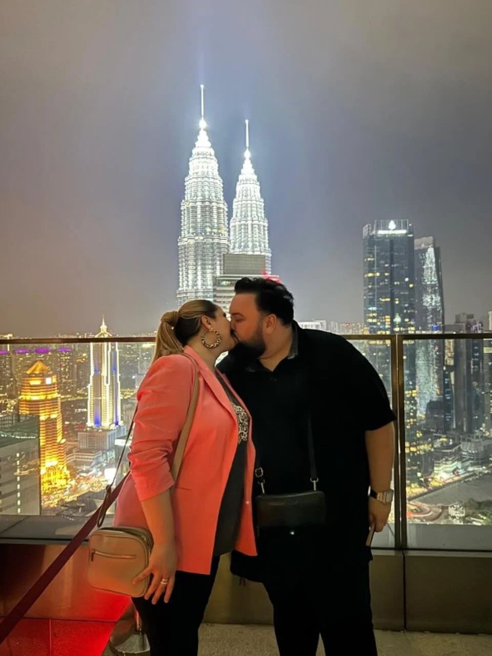 Jacques Houdek i partnerica se ljube ispred osvijetljenih nebodera