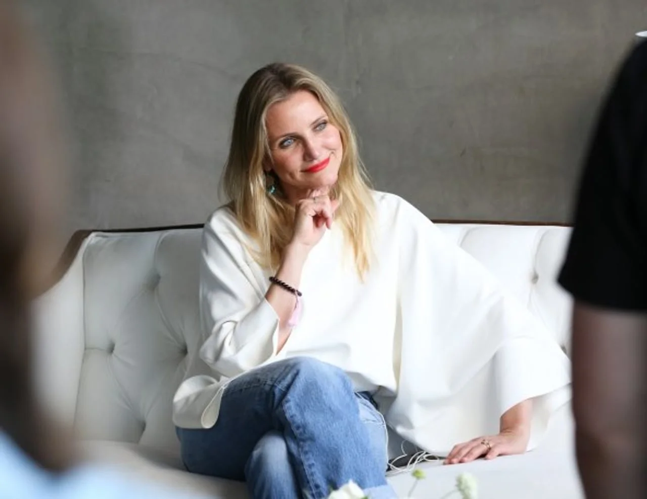 Cameron Diaz sjedi na bijelom kauču u bijeloj bluzi