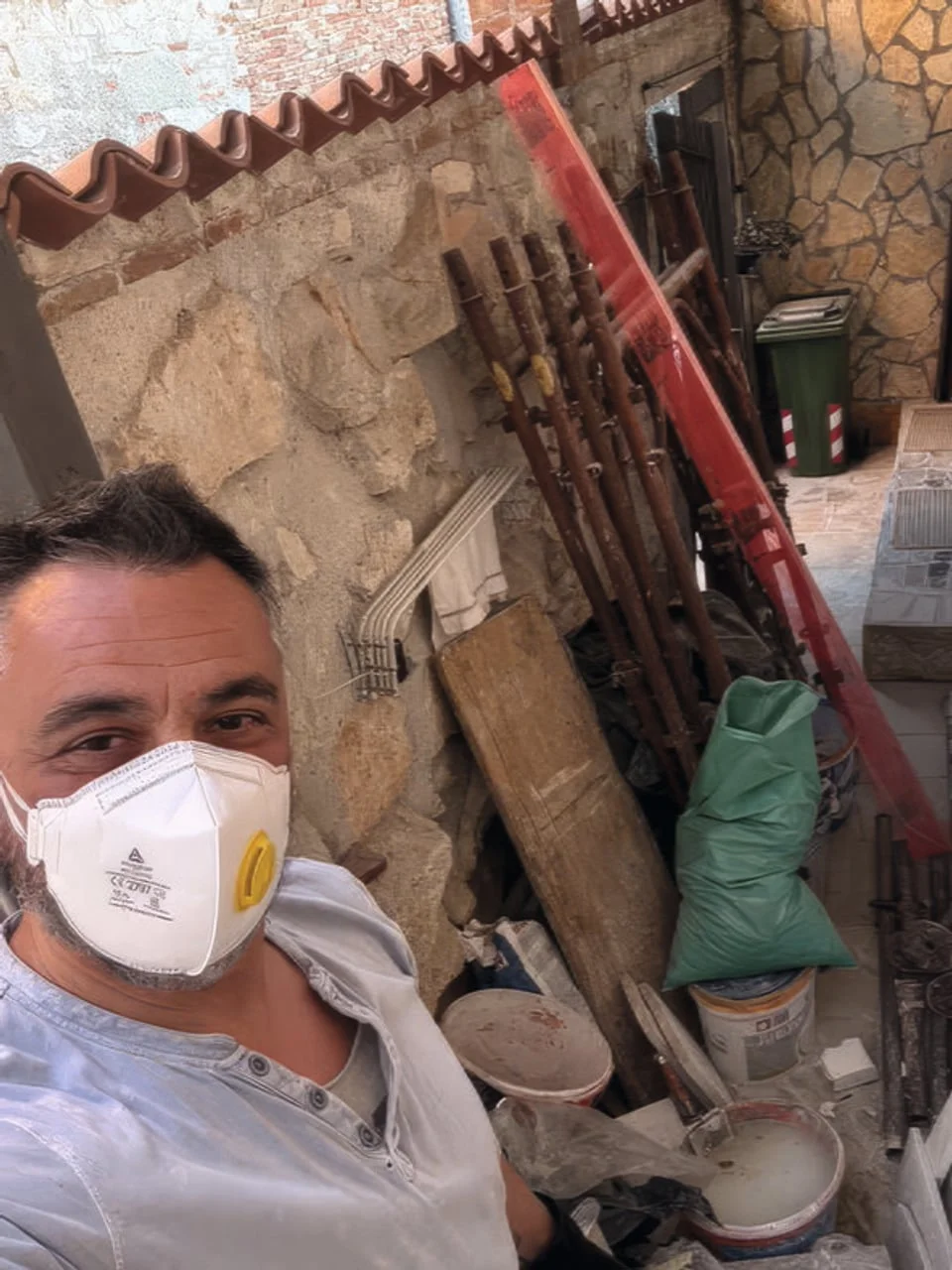 Muškarac s zaštitnom maskom u dvorištu s građevinskim materijalom