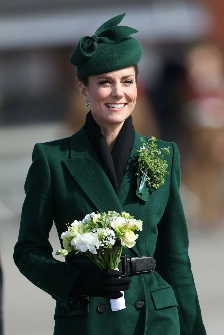 Kate Middleton u tamnozelenom kaputu i šeširu s buketom cvijeća