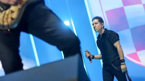 Glazbenik Tiho Orlić pjeva u crnoj košulji na koncertnoj pozornici