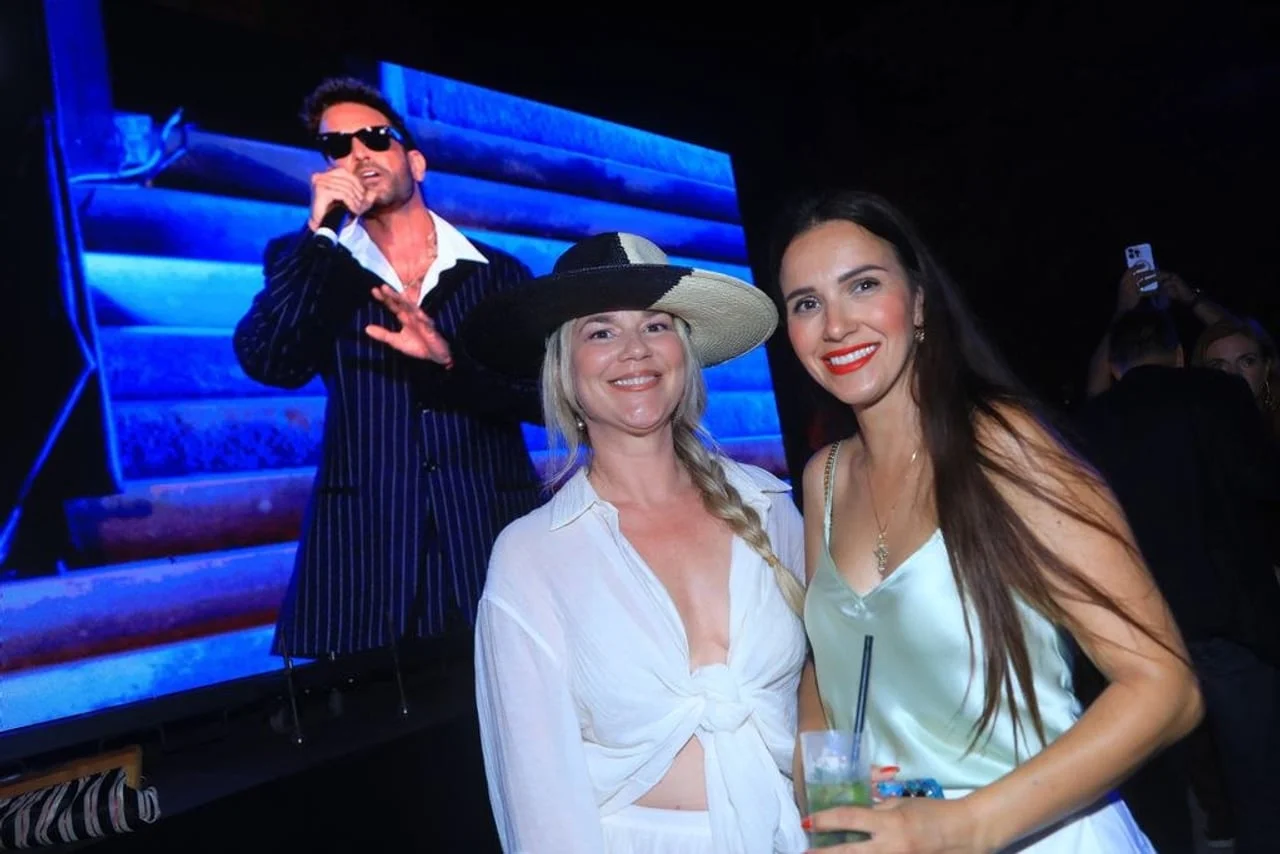 Dvije žene u elegantnoj odjeći ispred velikog ekrana s pjevačem