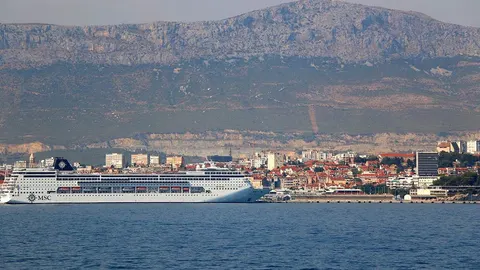 Veliki putnički brod MSC usidren u luci grada uz planine u pozadini