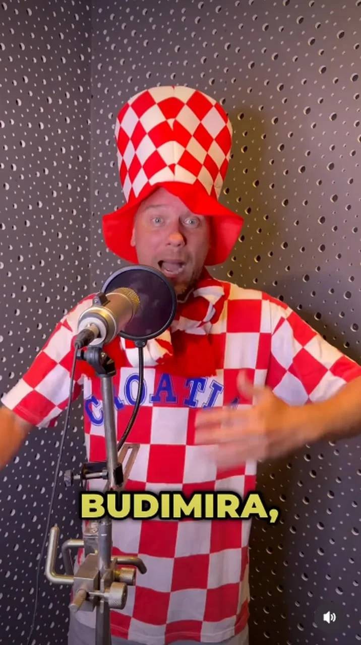 Muškarac u navijačkoj odjeći gestikulira tijekom snimanja