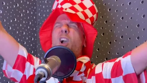 Muškarac u crveno-bijelom šeširu pjeva u studio mikrofon