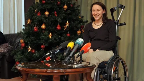 Sandra Paović u kolicima sjedi pored novinarskih mikrofona i bora