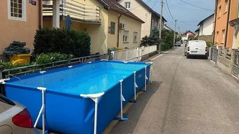 Plavi pravokutni bazen na betonskom trotoaru uz cestu u naselju