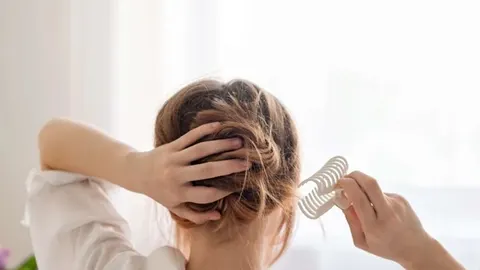 Žena s smeđom kosom pravi punđu koristeći bijelu šnalicu