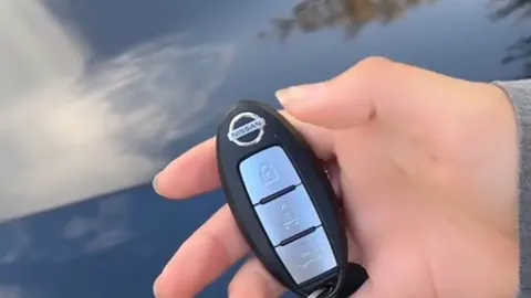 Ruka koja drži moderni Nissan daljinski upravljač za zaključavanje automobila
