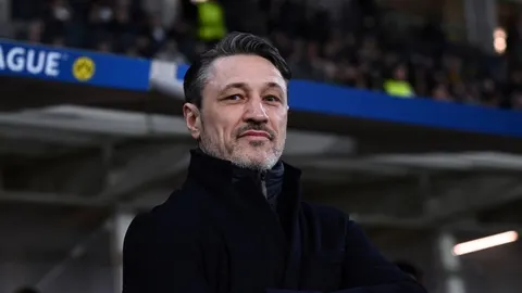 Portret Nikole Kovača u crnom kaputu na nogometnom stadionu