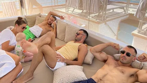 Grupa mladih ljudi i dijete opuštaju se na sunčanom palubnom prostoru jahte