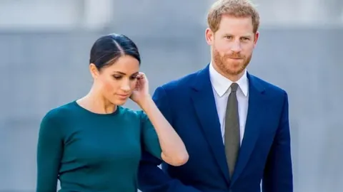 Princ Harry u plavom odelu i Meghan Markle u tamnozelenoj haljini