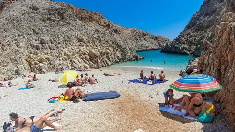 Tirkizna morska uvala s kamenj rekom i stijenama, okružena visokim hridima