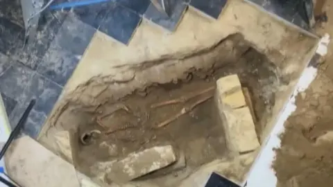 Arheološko nalazište sa skeletom u zemlji ispod ostataka kamenog poda crkve.