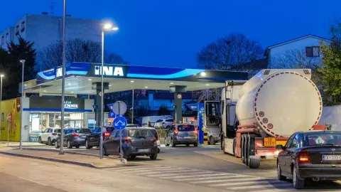 Osvijetljena benzinska postaja Ina navečer s nekoliko automobila i cisternom.