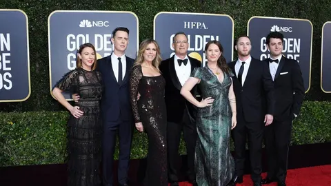 Grupa ljudi u svečanim odjećama na crvenom tepihu ispred Golden Globe pozadine