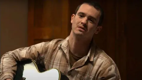 Portret Ivana Glowatzkya u kariranom košulji s gitarom