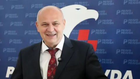 Mislav Kolakušić se smiješi ispred stranačke pozadine Pravo i Pravda