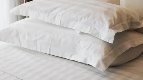 Dva bijela jastuka složena jedan na drugoga na krevetu