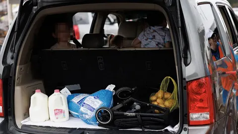 Otvoren prtljažnik automobila s mliječnim proizvodima, namirnicama i dječjim kolicima