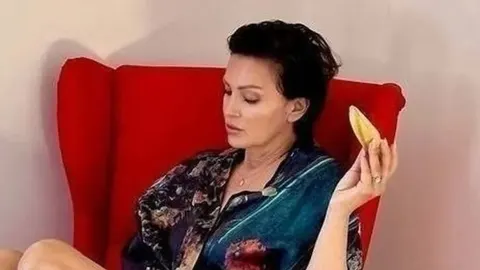 Pjevačica Nina Badrić u svilenom badelinu sjedi u crvenom fotelju