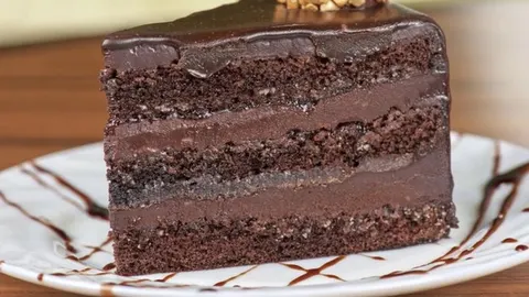 Komad čokoladne torte s glazurom i slojevima kreme na bijelom tanjuru