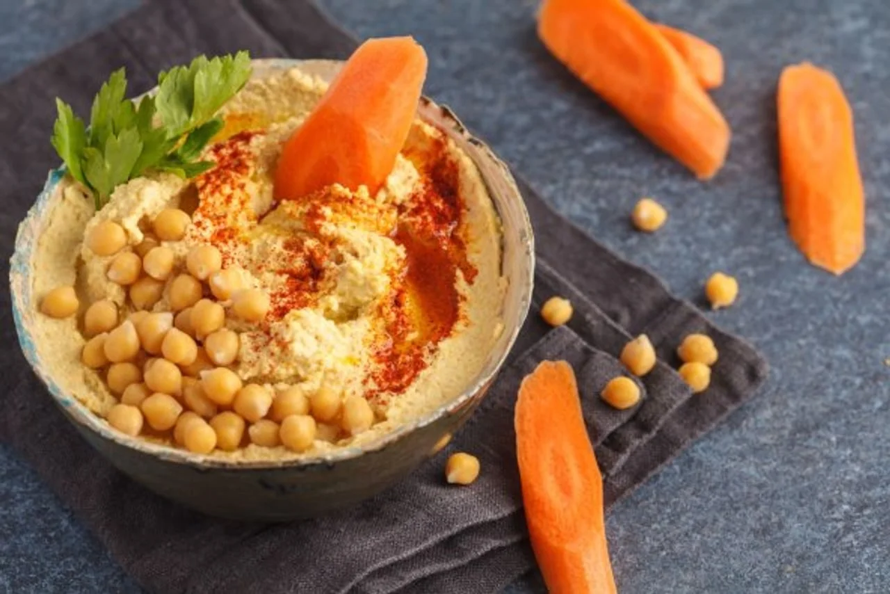 Hummus s pivkom i komadićima mrkve na tamnoj podlozi