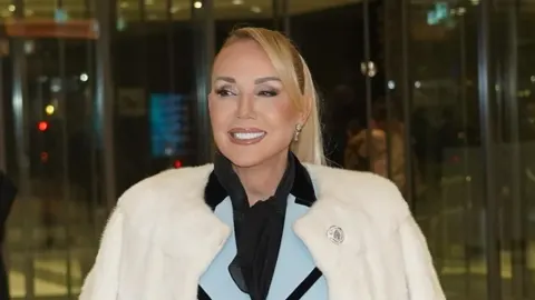 Lepa Brena s plavom kosom u bijeloj bundi i sa šminkom na licu.