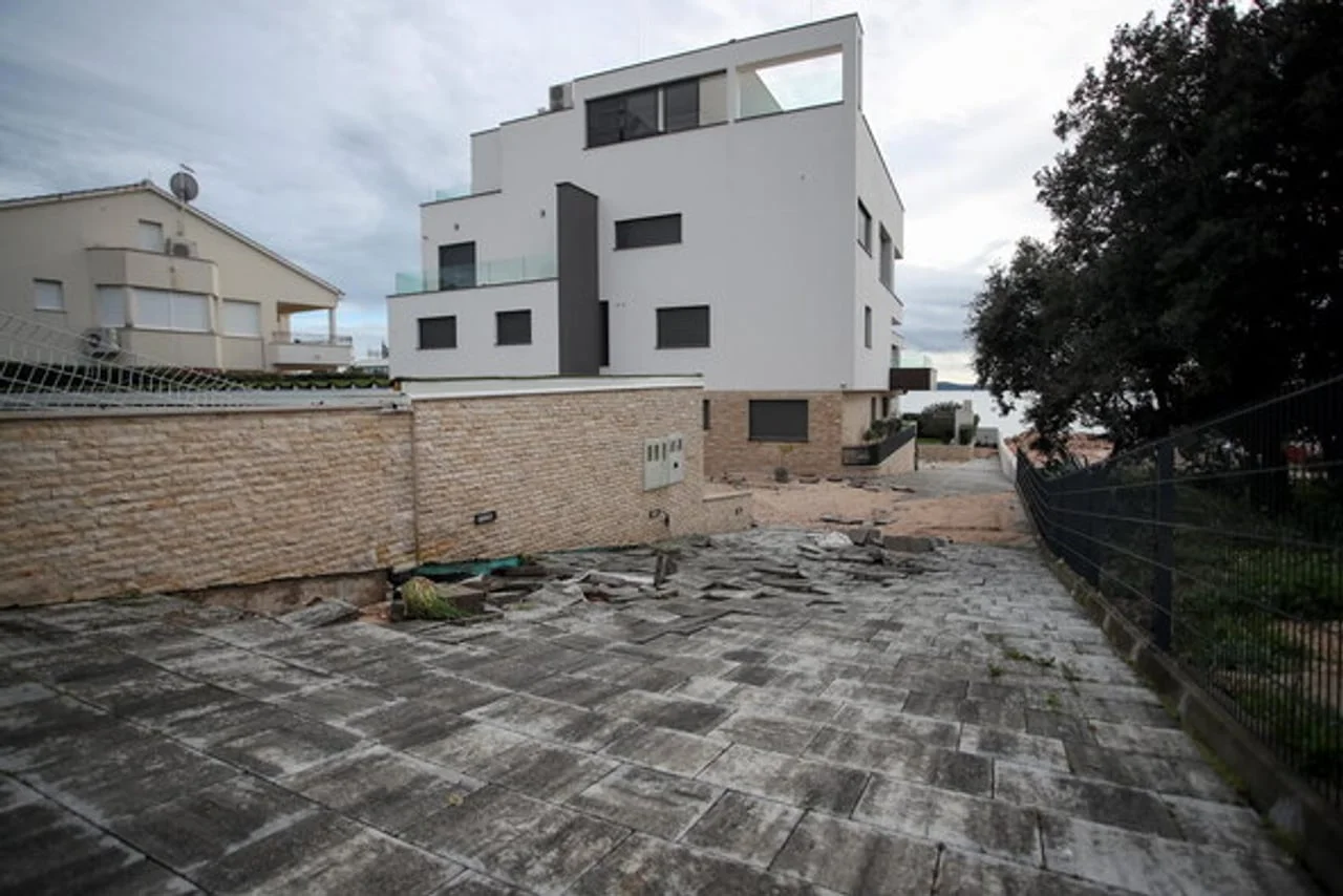 Moderna bijela vila s kamenim zidom i popločanim dvorištem