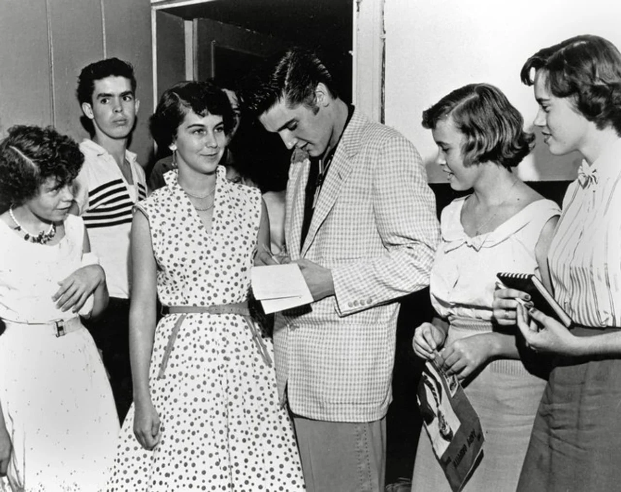 Mladi Elvis Presley u kariranom sakou okružen grupom devojaka
