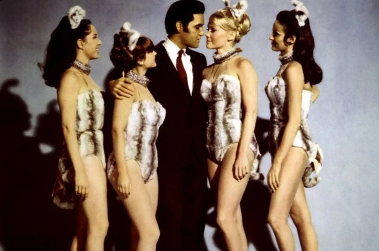 Elvis Presley u crnom odelu sa četiri žene u kostimima od krzna