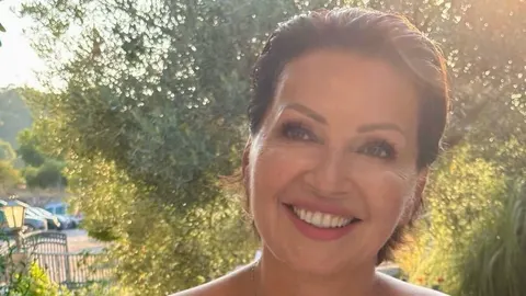 Portret nasmijane Nine Badrić na otvorenom prostoru s drvima u pozadini