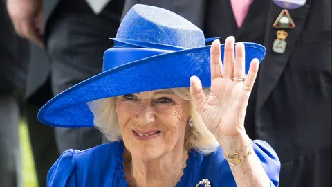 Kraljica Camilla u plavom šeširu i haljini pozdravlja rukom