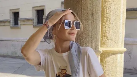 Danijela Martinović u bijeloj majici i sunčanim naočalama ispred stupa