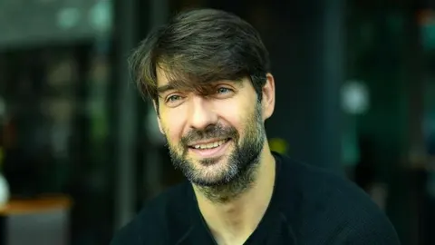 Portret Vedrana Ćorluke s blagim osmijehom i bradom