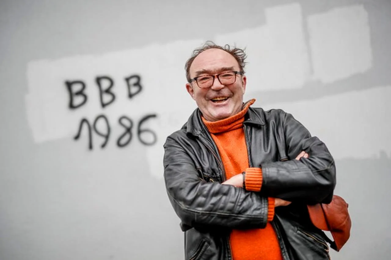 Portret nasmijanog Damira Šabana u crnoj kožnoj jakni i narančastom džemperu