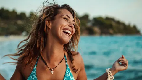 Sretna žena s raširenim rukama koja se smije na plaži