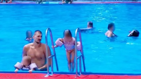 Nikola Jokić sjedi na rubu plavog bazena pored djeteta