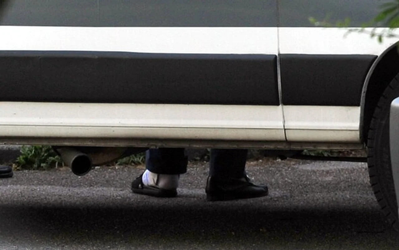 Detalj nogu i cipela osobe pored automobila