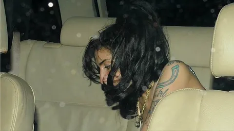 Profil Amy Winehouse s velikim crnim frizurom u automobilu