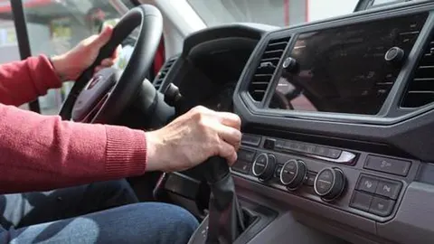 Ruka vozača na ručici mjenjača i upravljaču u modernom automobilu