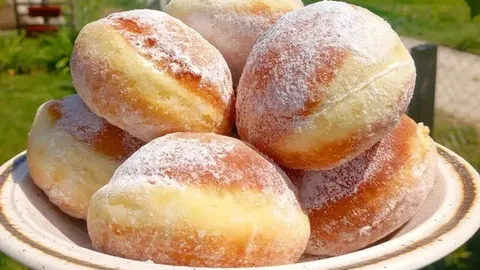 Hrpa domaćih prženih krofni posutih šećerom na bijelom tanjuru